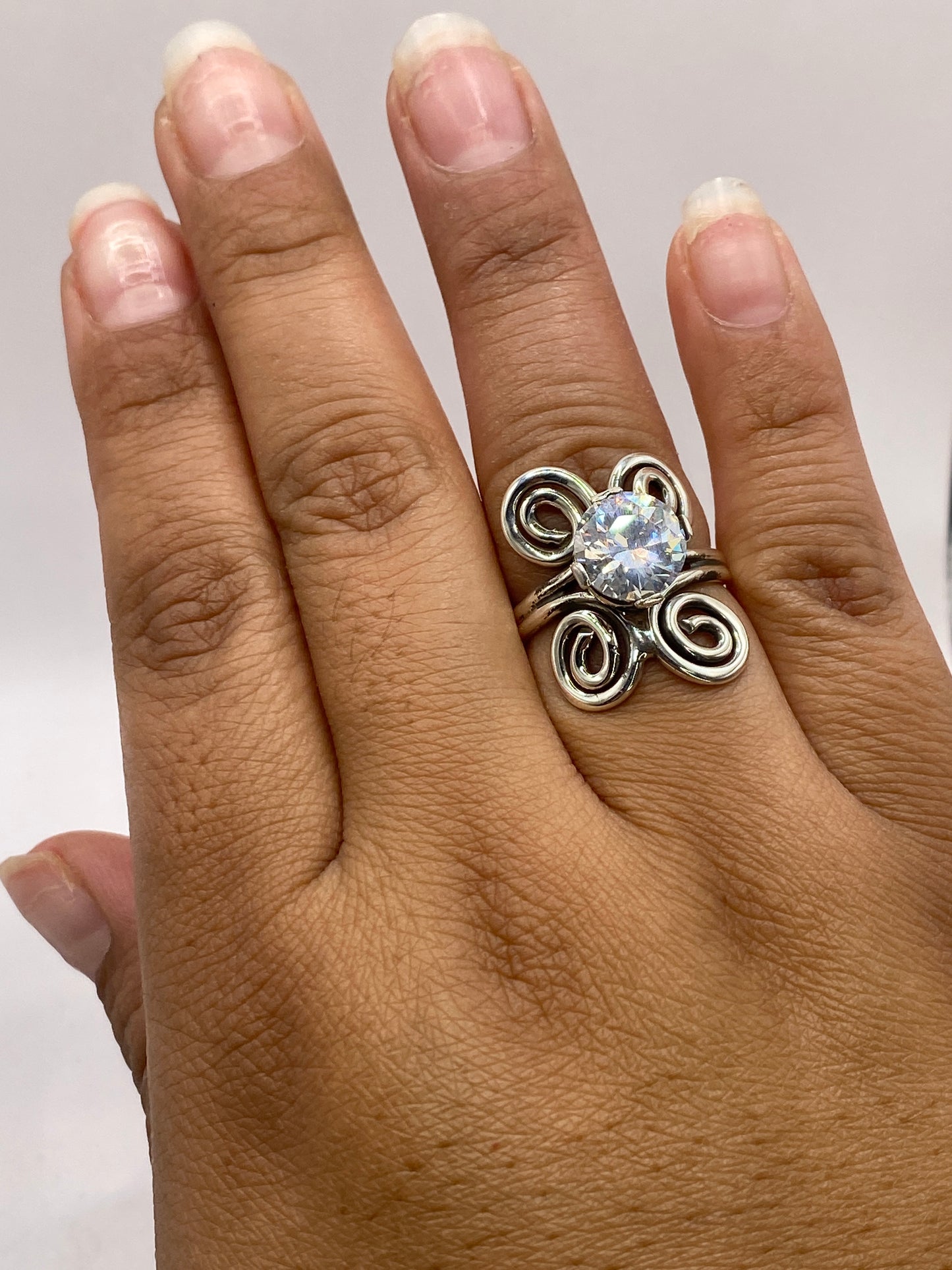 Anillo de circonia cristalina en la mano de mujer sobre fondo claro