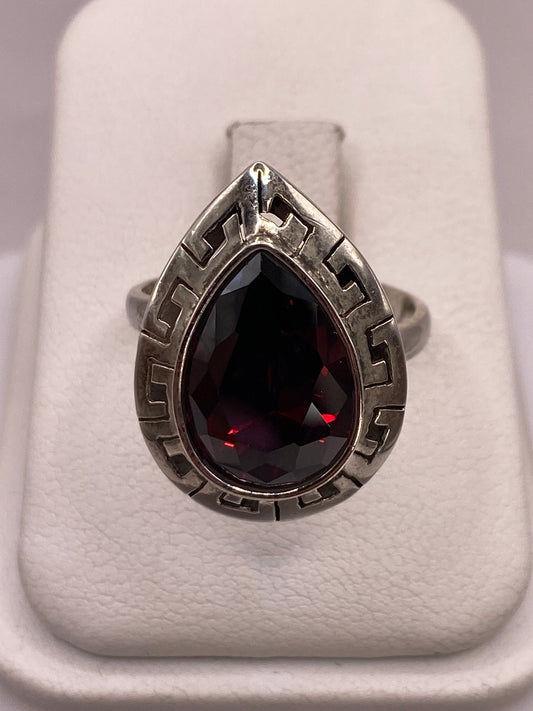 Anillo solitario de plata .925 con circonia roja facetada en la mano de una mujer