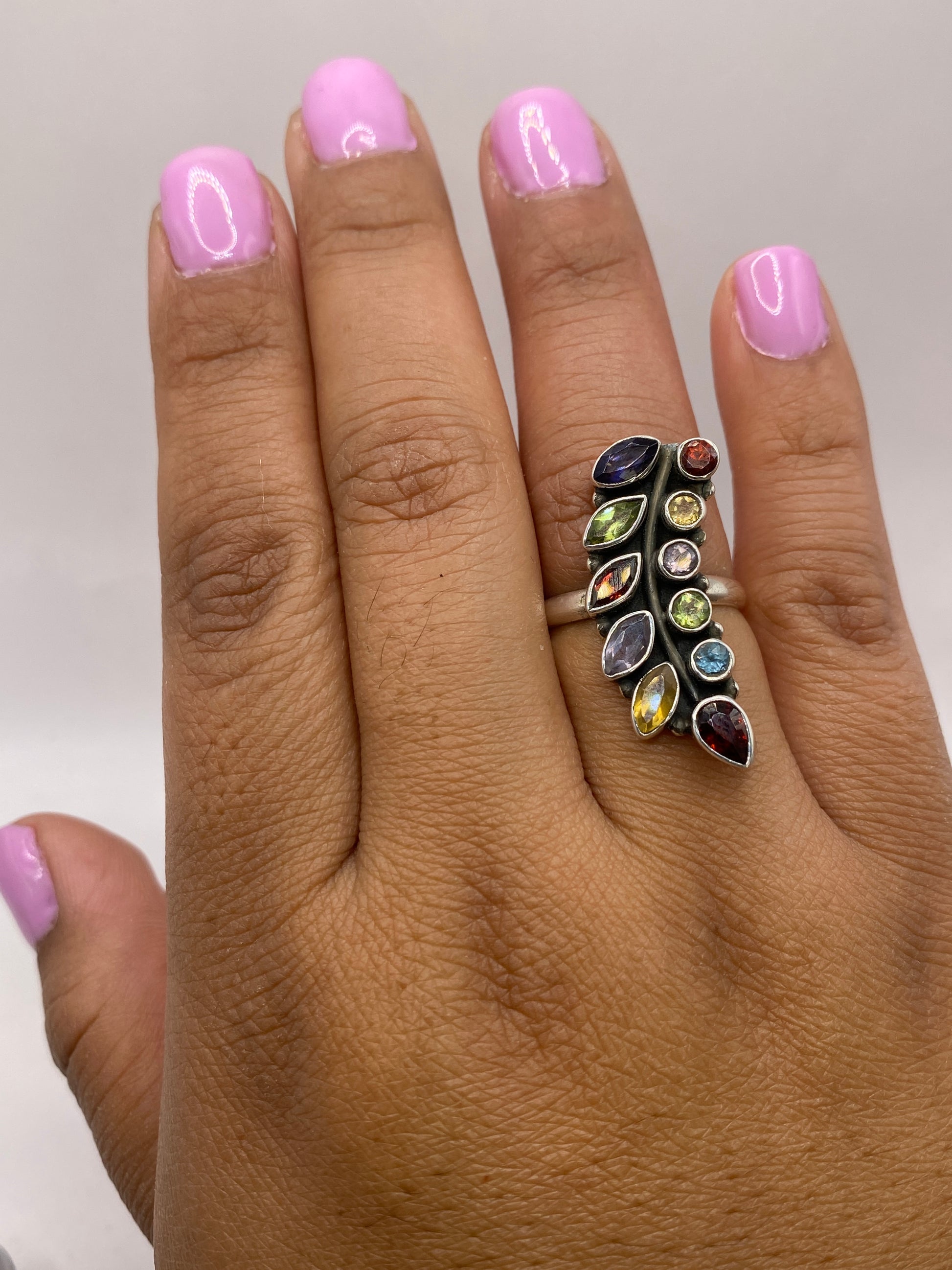 Anillo de plata multicolor puesto en mano de mujer con brillo natural