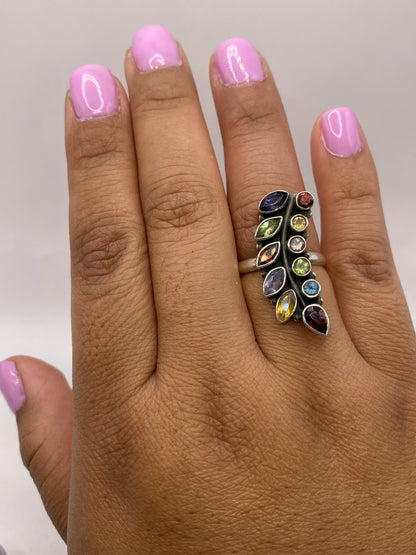 Anillo de plata multicolor puesto en mano de mujer con brillo natural
