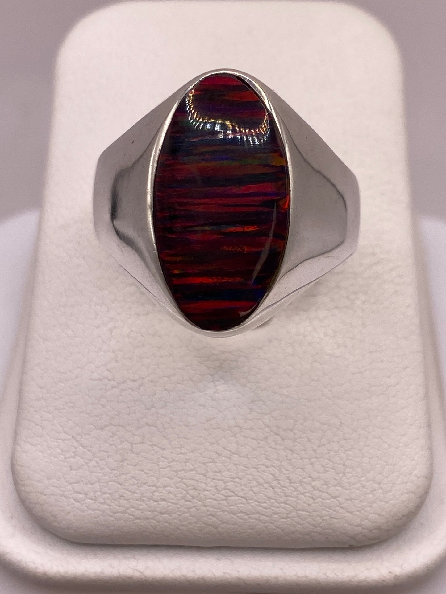 Anillo solitario de plata .925 con ópalo de fuego multicolor, tono rojo y naranja dominante sobre dedo de mujer