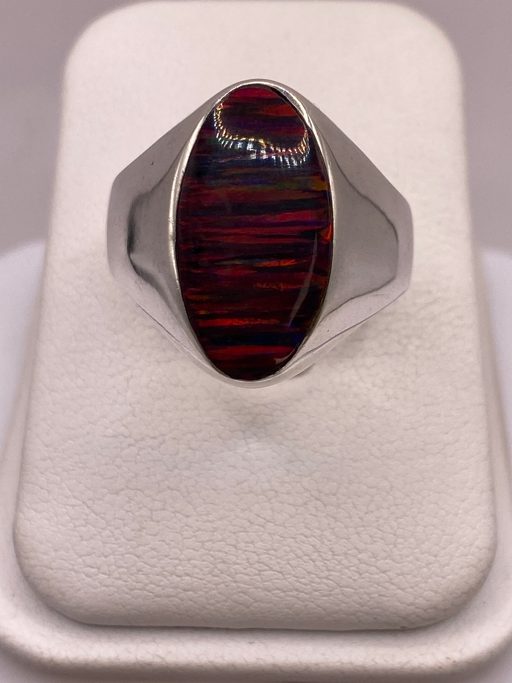 Anillo solitario de plata .925 con ópalo de fuego multicolor, tono rojo y naranja dominante sobre dedo de mujer