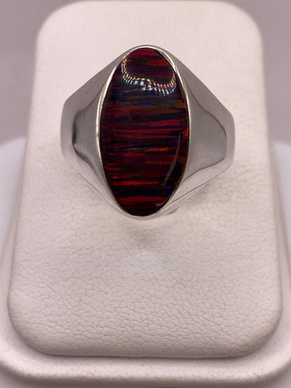 Anillo solitario de plata .925 con ópalo de fuego multicolor, tono rojo y naranja dominante sobre dedo de mujer