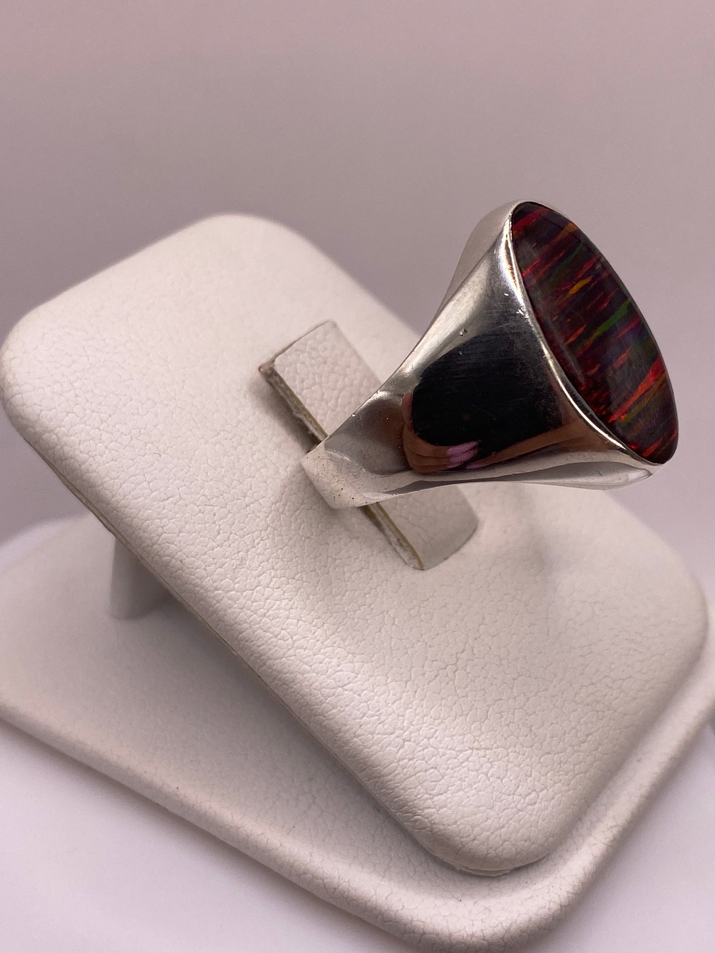 Vista frontal del anillo ópalo fuego con juego de colores verde, azul y rojo en la gema natural