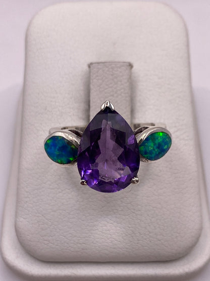 Anillo de plata con ópalo de fuego púrpura en bandeja blanca, mostrando el juego de colores