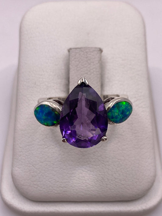 Anillo de plata con ópalo de fuego púrpura en bandeja blanca, mostrando el juego de colores