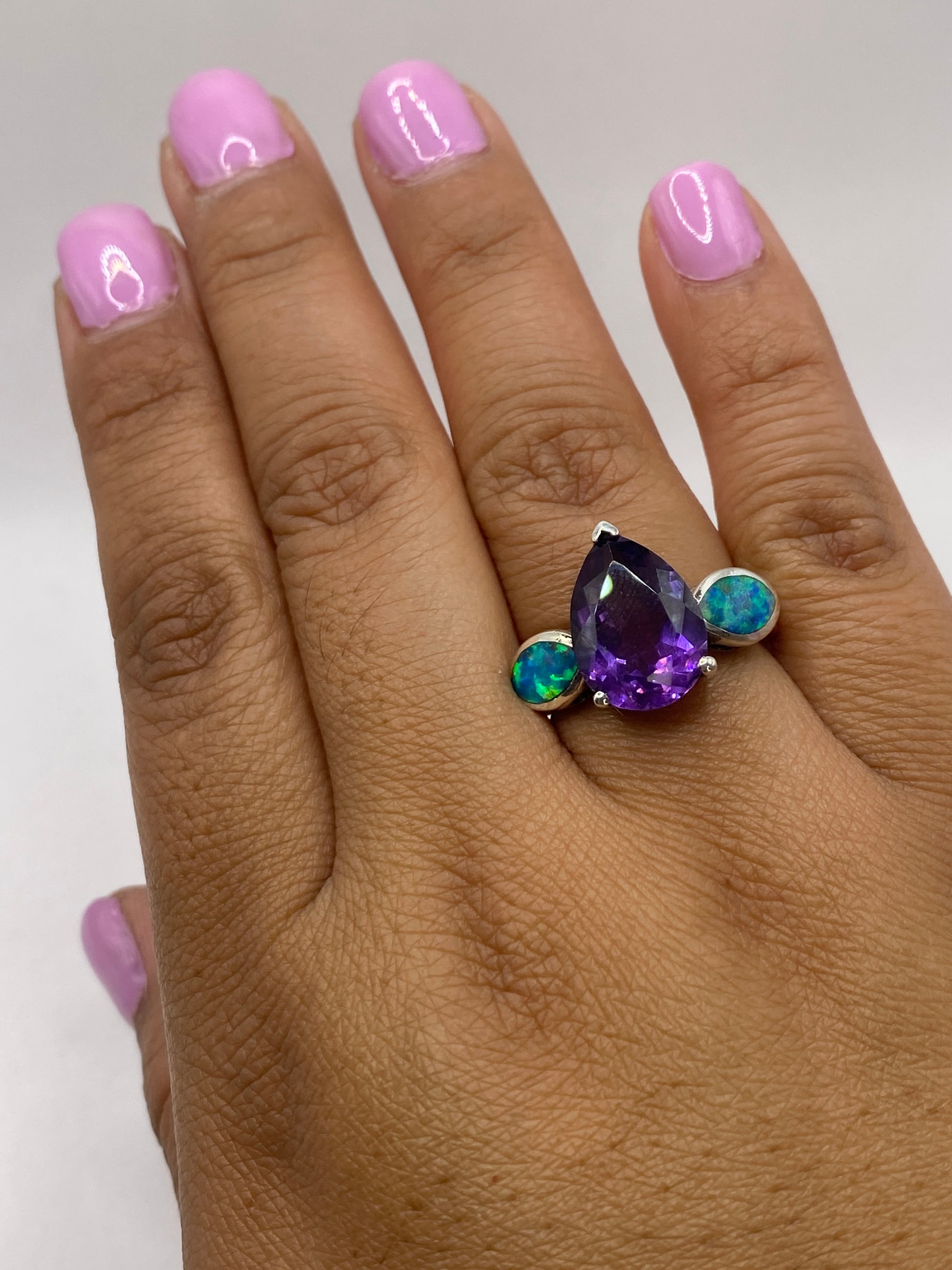 Anillo de plata con ópalo de fuego en la mano de una mujer, brillo natural del ópalo