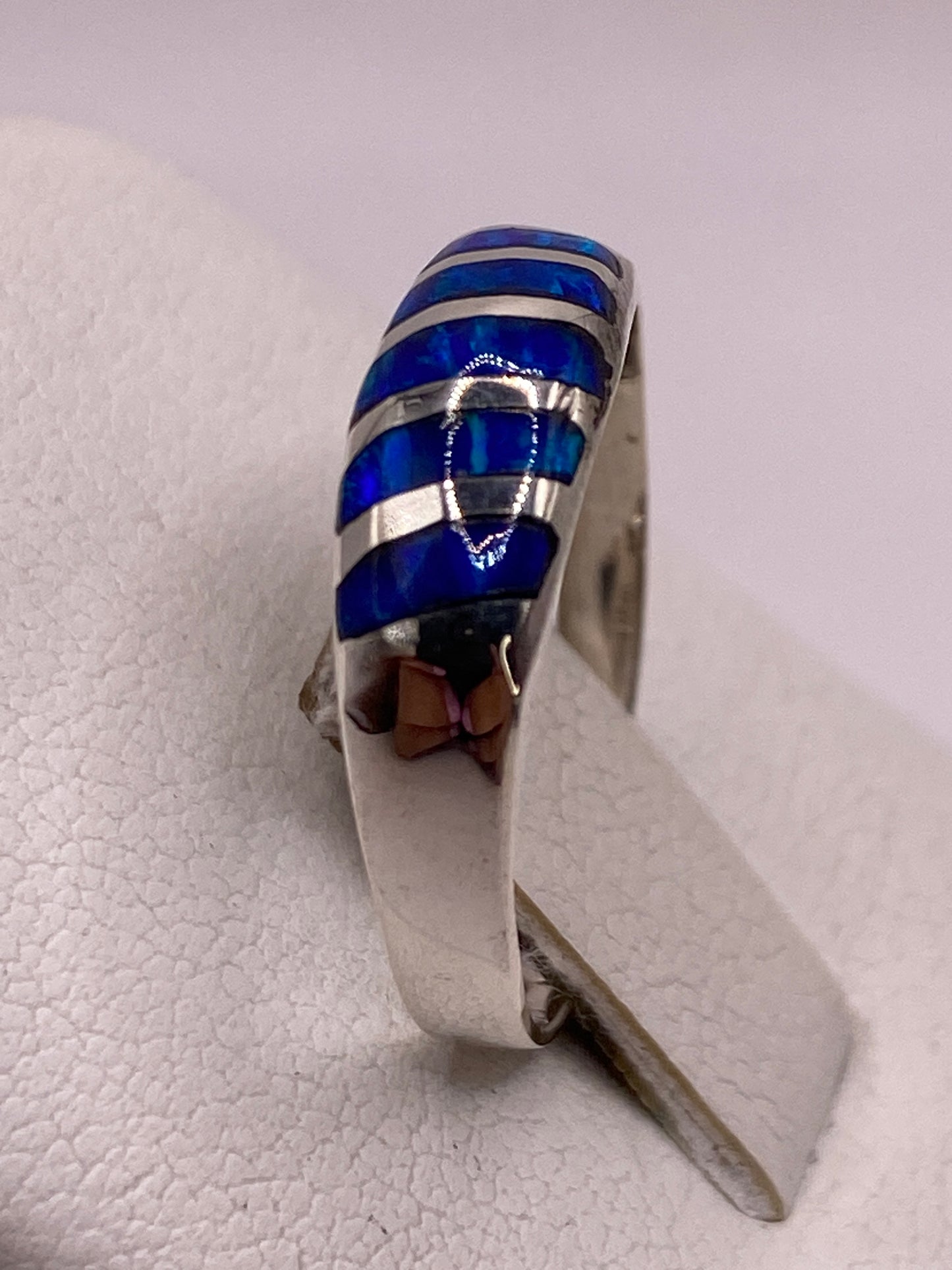 Anillo de ópalo de fuego azul puesto en dedo, mostrando el brillo natural de la piedra
