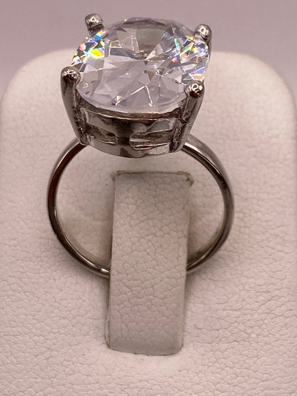 Anillo solitario de plata con circonia cristalina engastado en cuatro puntas sobre fondo blanco