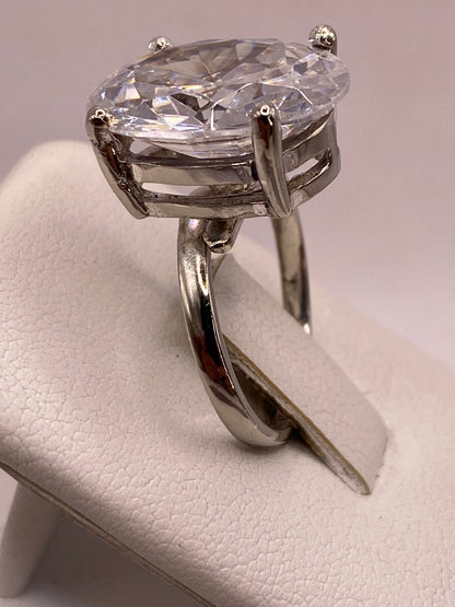 Anillo solitario en el dedo de una mujer con esmalte rosa, luz reflejada en la piedra