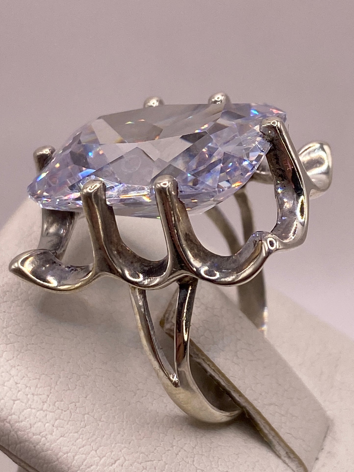 Anillo en la mano con esmalte de uñas rosa, mostrando el brillo diamantino de la circonia