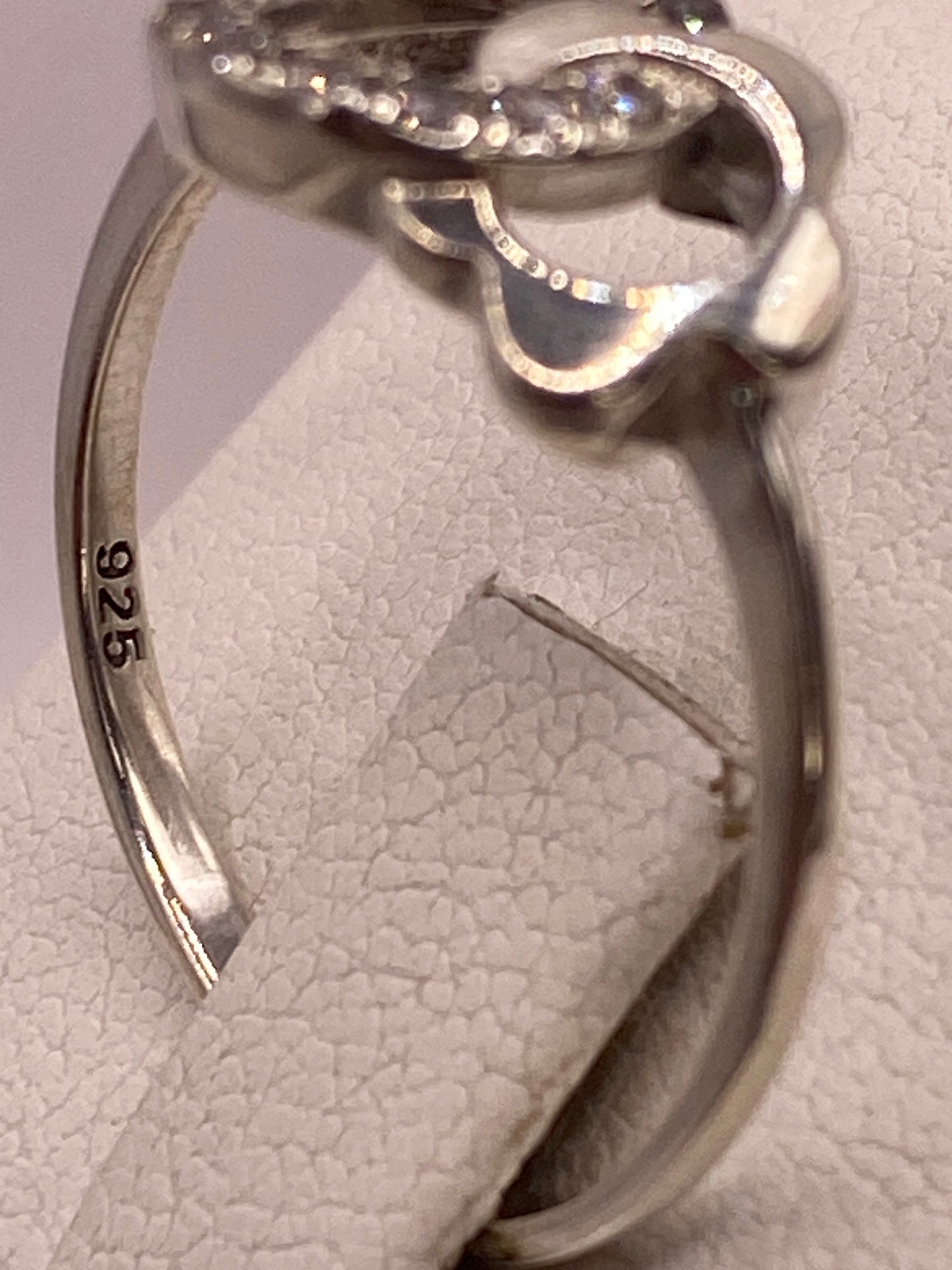 Anillo solitario en mano de mujer con esmalte rosa, iluminando el brillo de la circonia