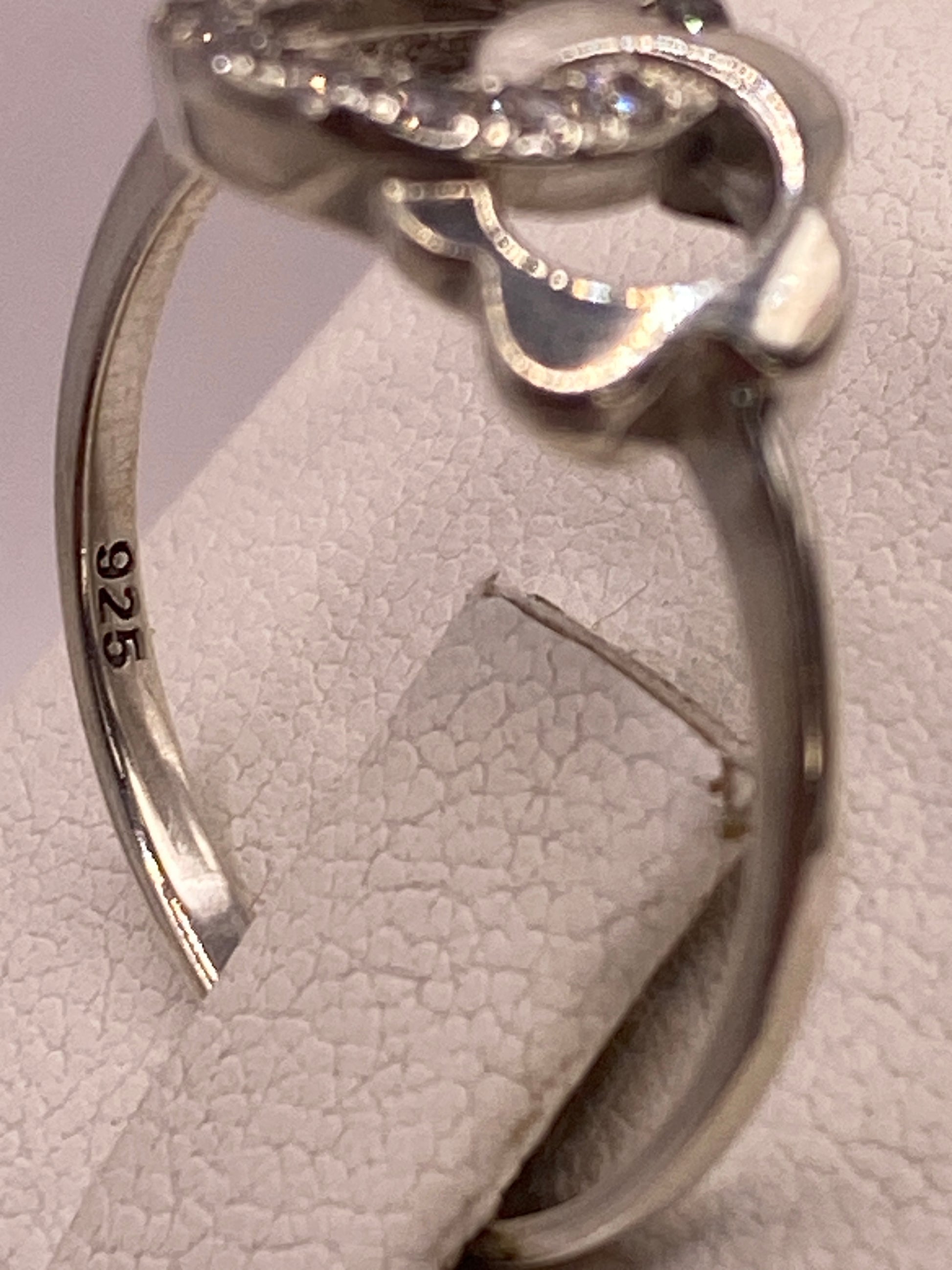 Anillo solitario en mano de mujer con esmalte rosa, iluminando el brillo de la circonia