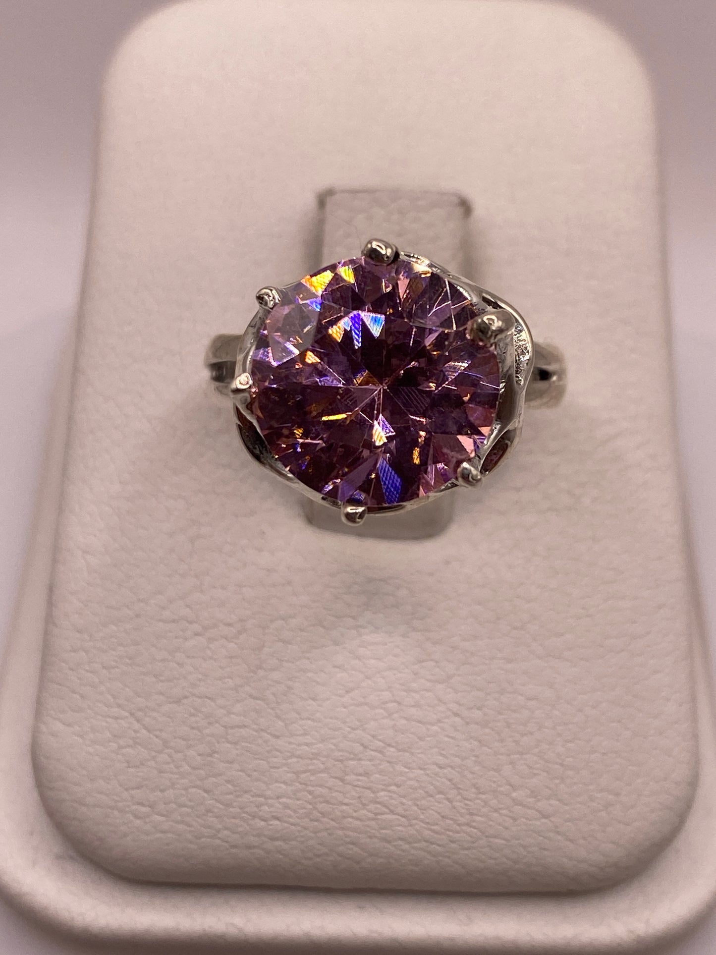 Anillo de plata solitario con circonia rosa facetada, frente directo sobre cojín blanco