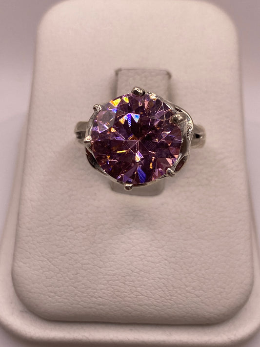 Anillo de plata solitario con circonia rosa facetada, frente directo sobre cojín blanco
