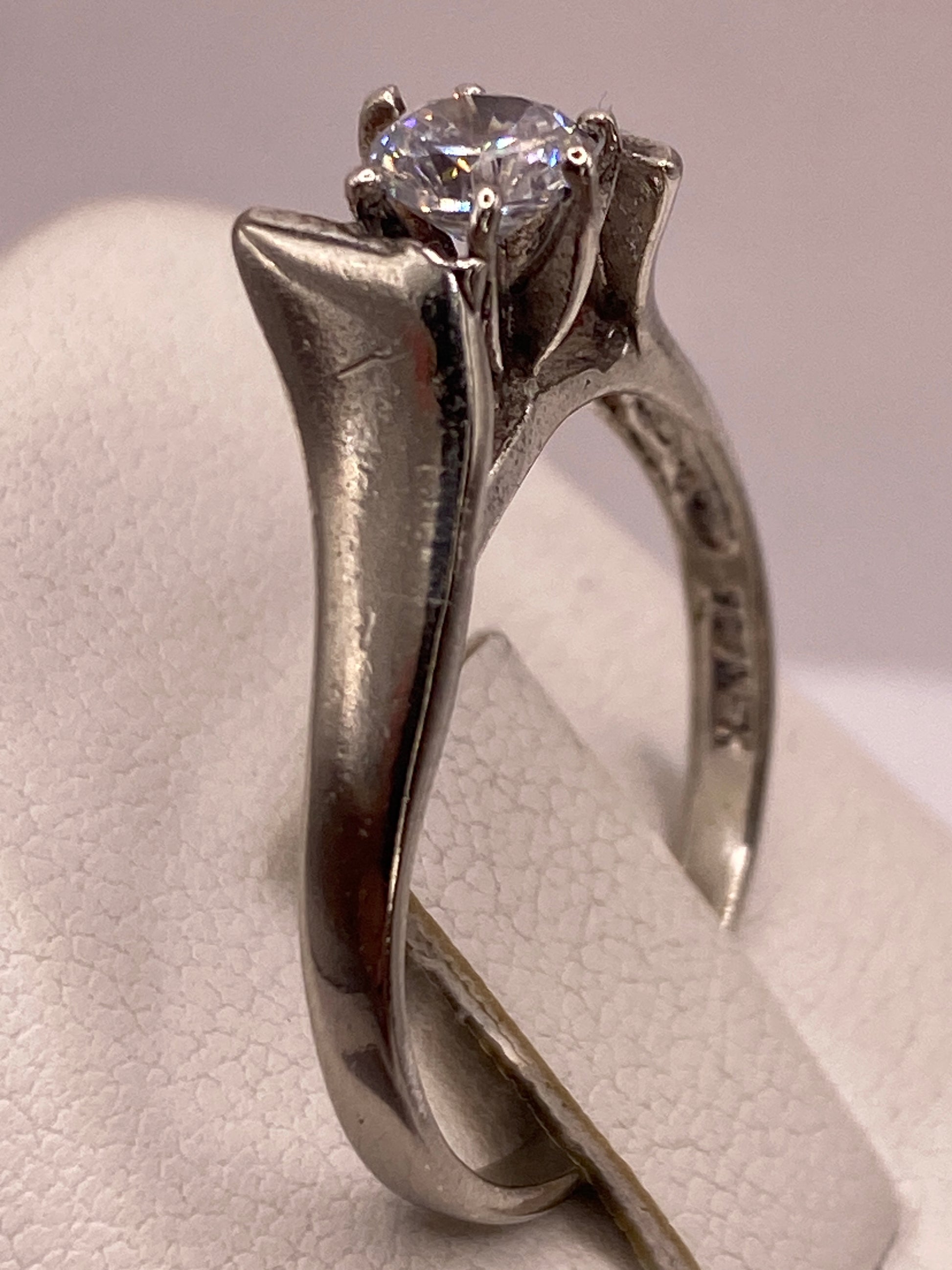 Anillo solitario en mano de mujer con manicura rosa, mostrando el brillo de la piedra
