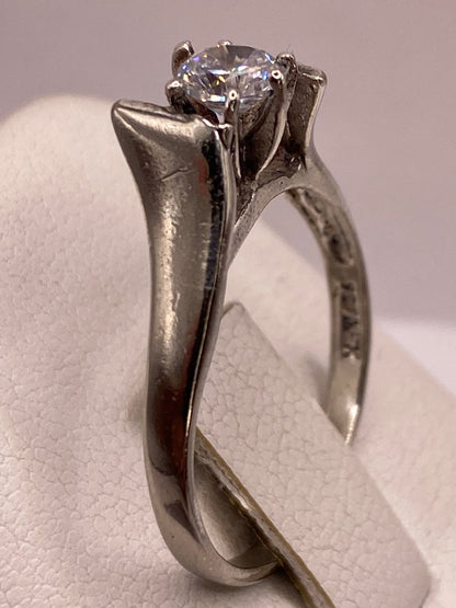 Anillo solitario en mano de mujer con manicura rosa, mostrando el brillo de la piedra