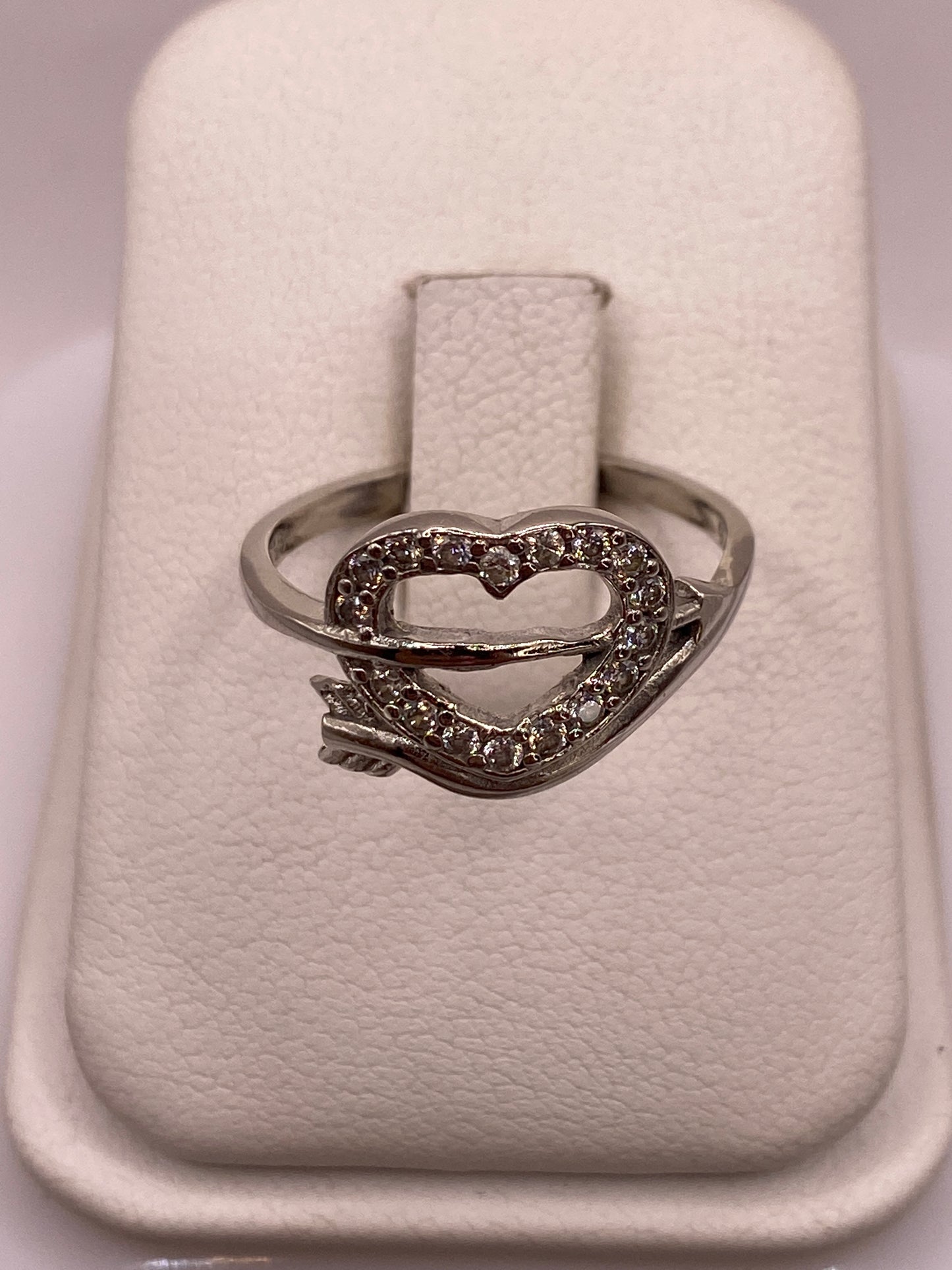 Anillo de plata solitario con circonia blanca brillante en la mano con uñas rosadas