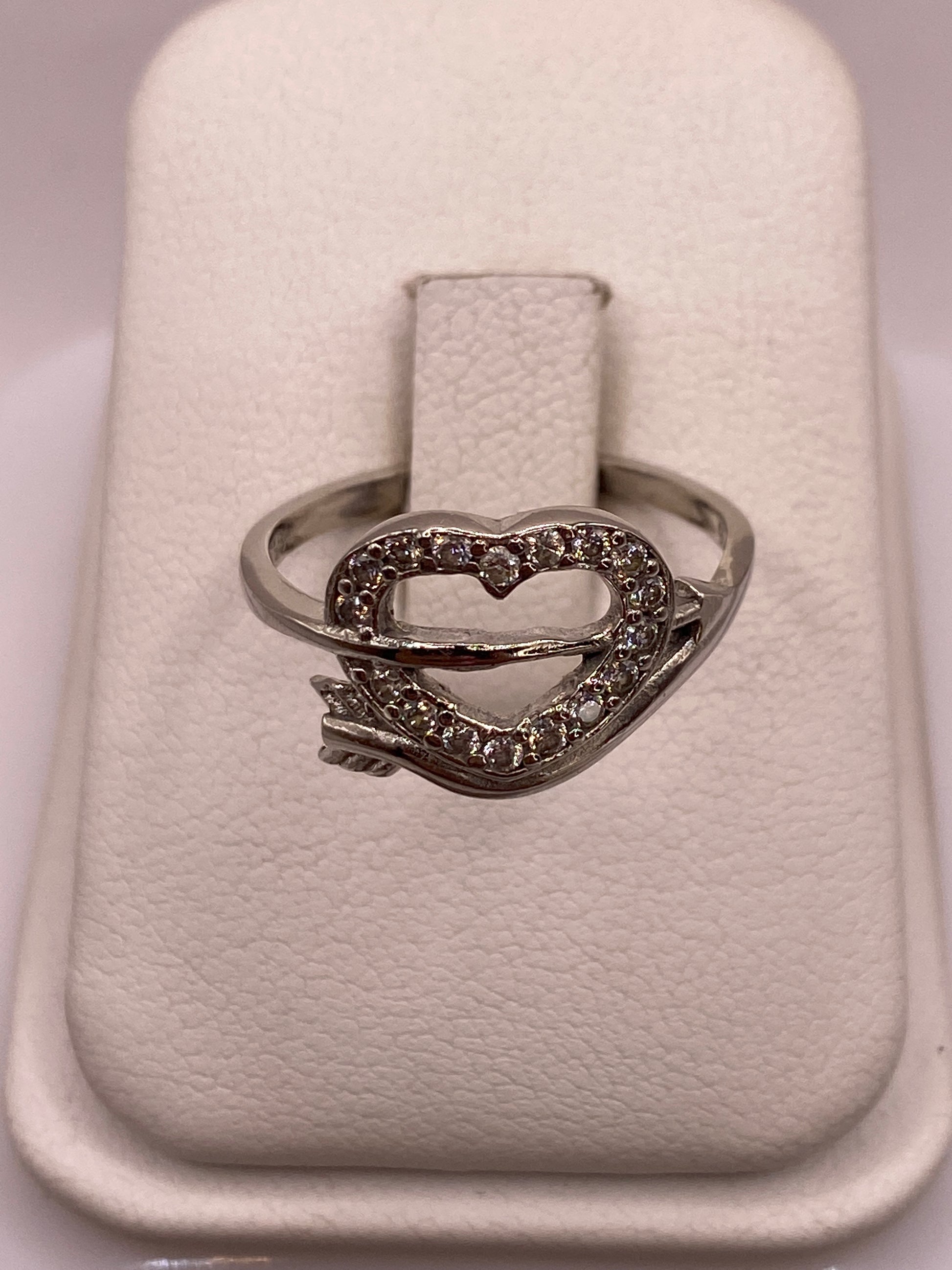 Anillo de plata solitario con circonia blanca brillante en la mano con uñas rosadas