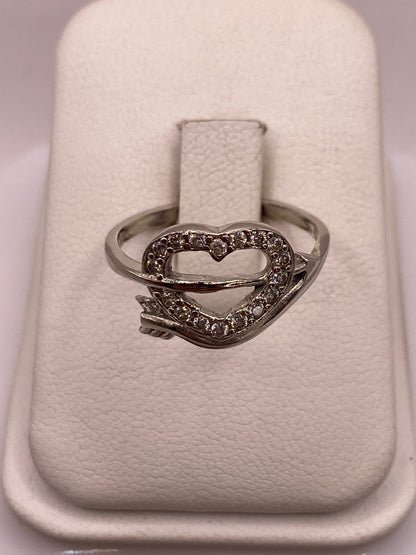Anillo de plata solitario con circonia blanca brillante en la mano con uñas rosadas