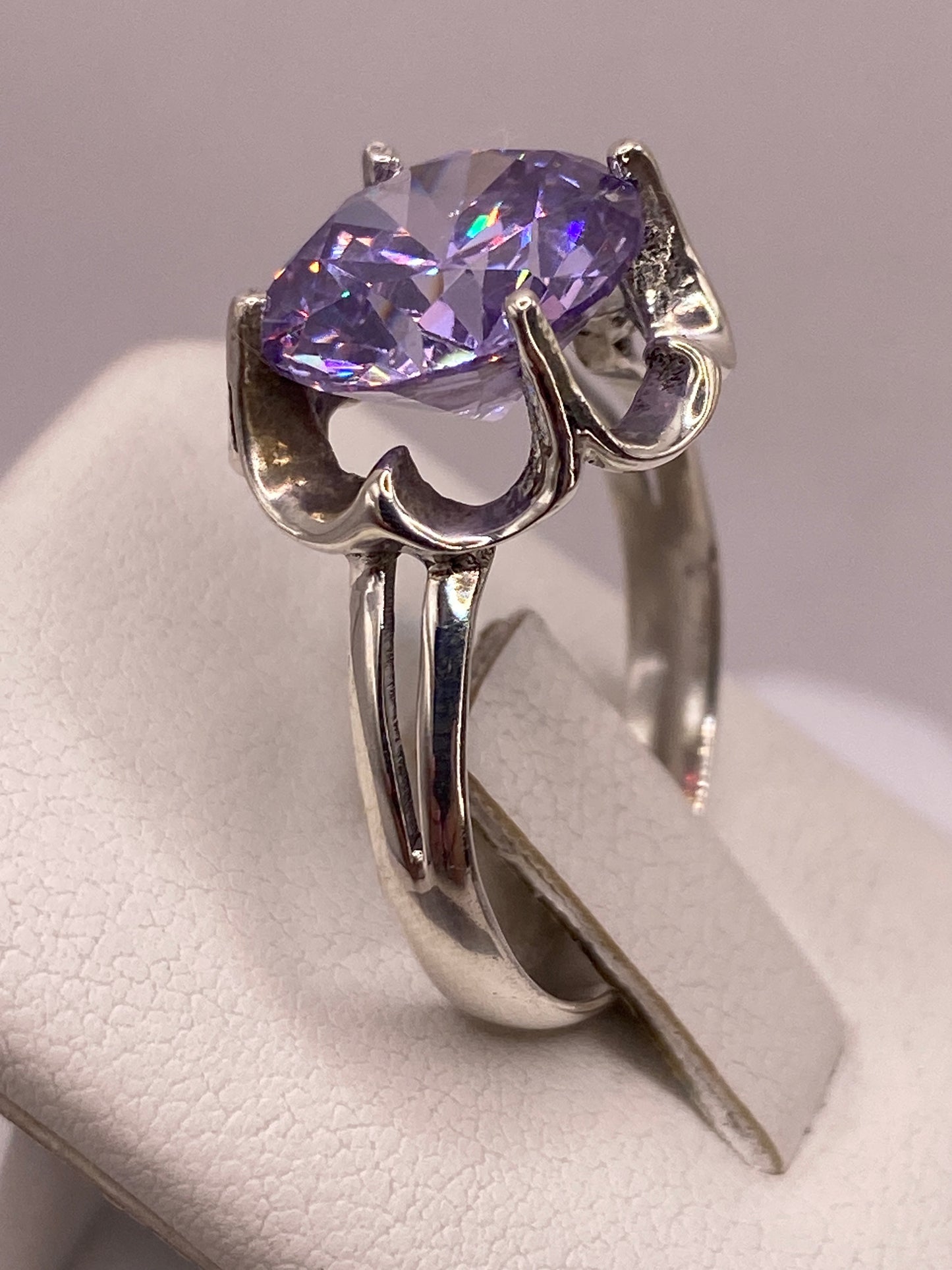 Anillo puesto en dedo con circonia morada brillando con fuego tipo diamante