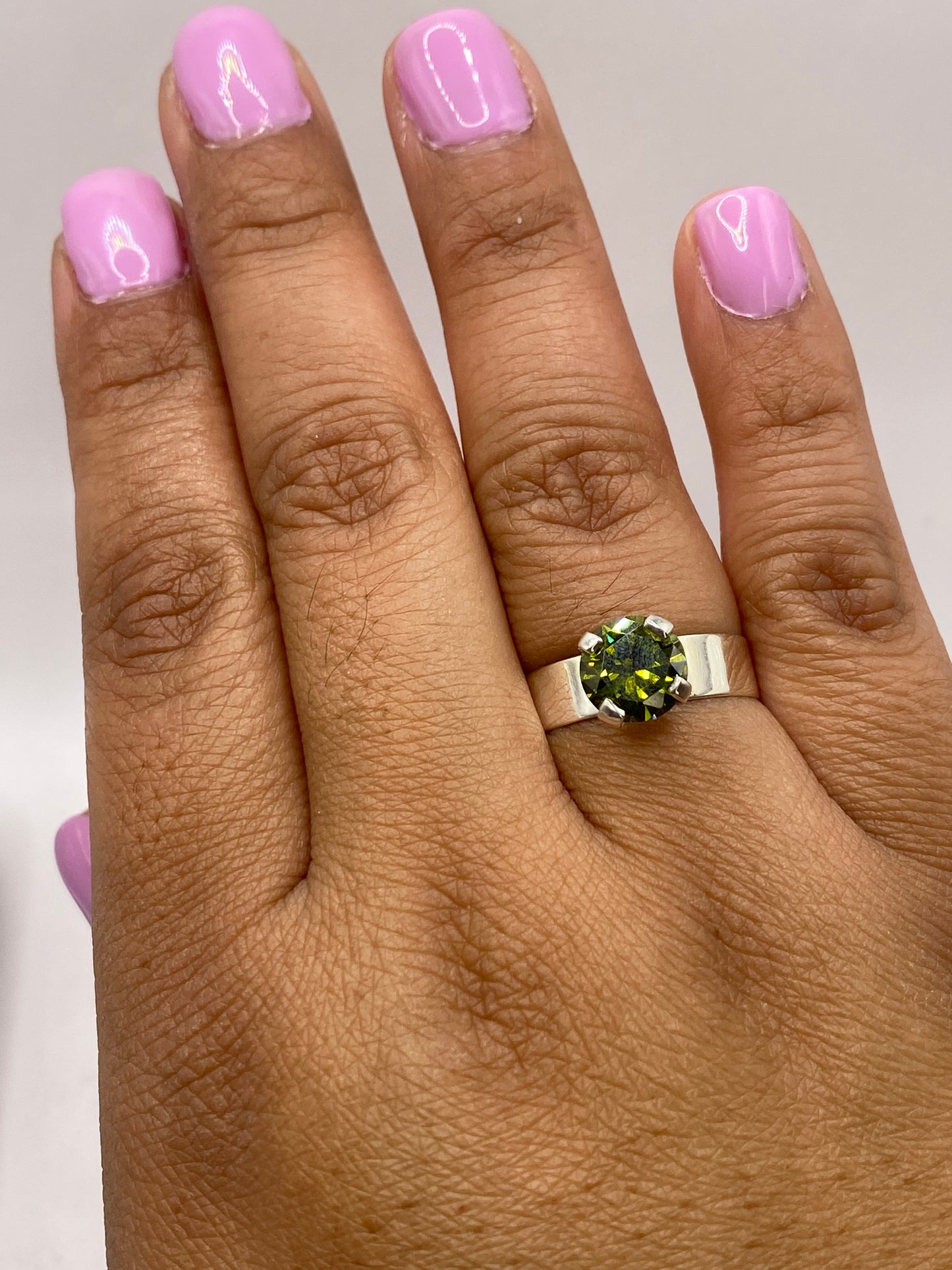 Anillo en mano modelando la piedra verde con luz natural, verificando hallmark 925
