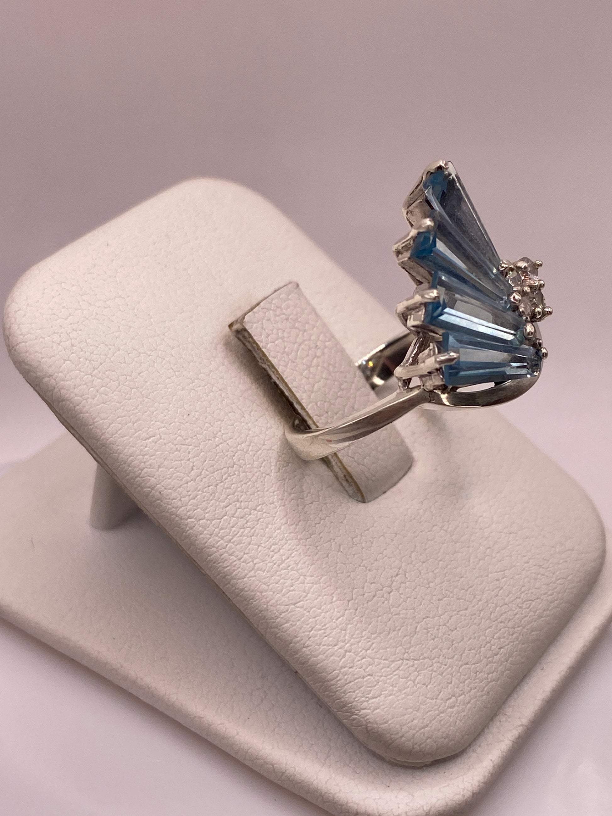 Anillo de plata engastado a mano con circonia azul facetada, vista lateral sobre dedo con uñas rosa
