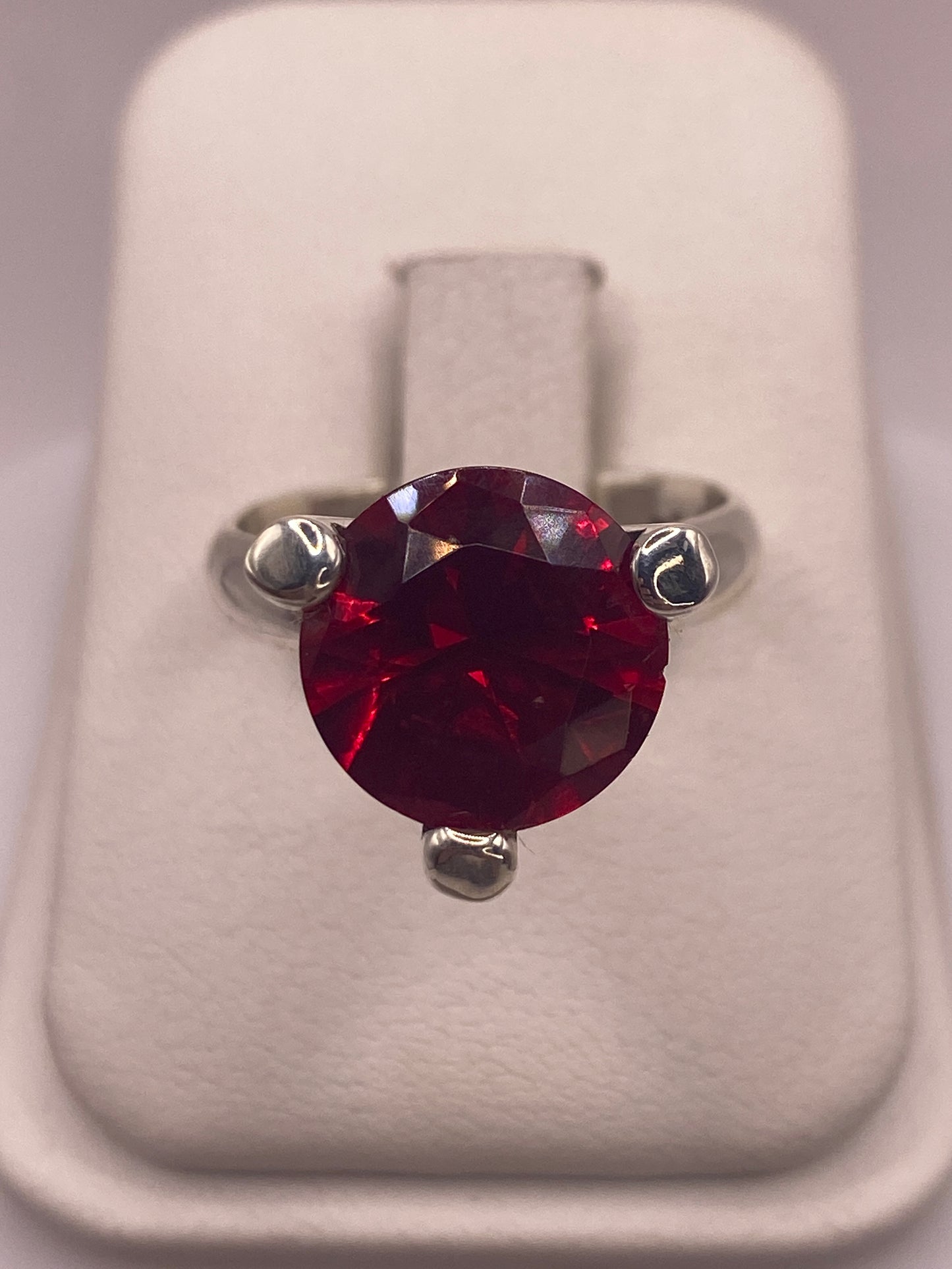Anillo solitario de plata .925 con circonia roja facetada en la mano de una mujer