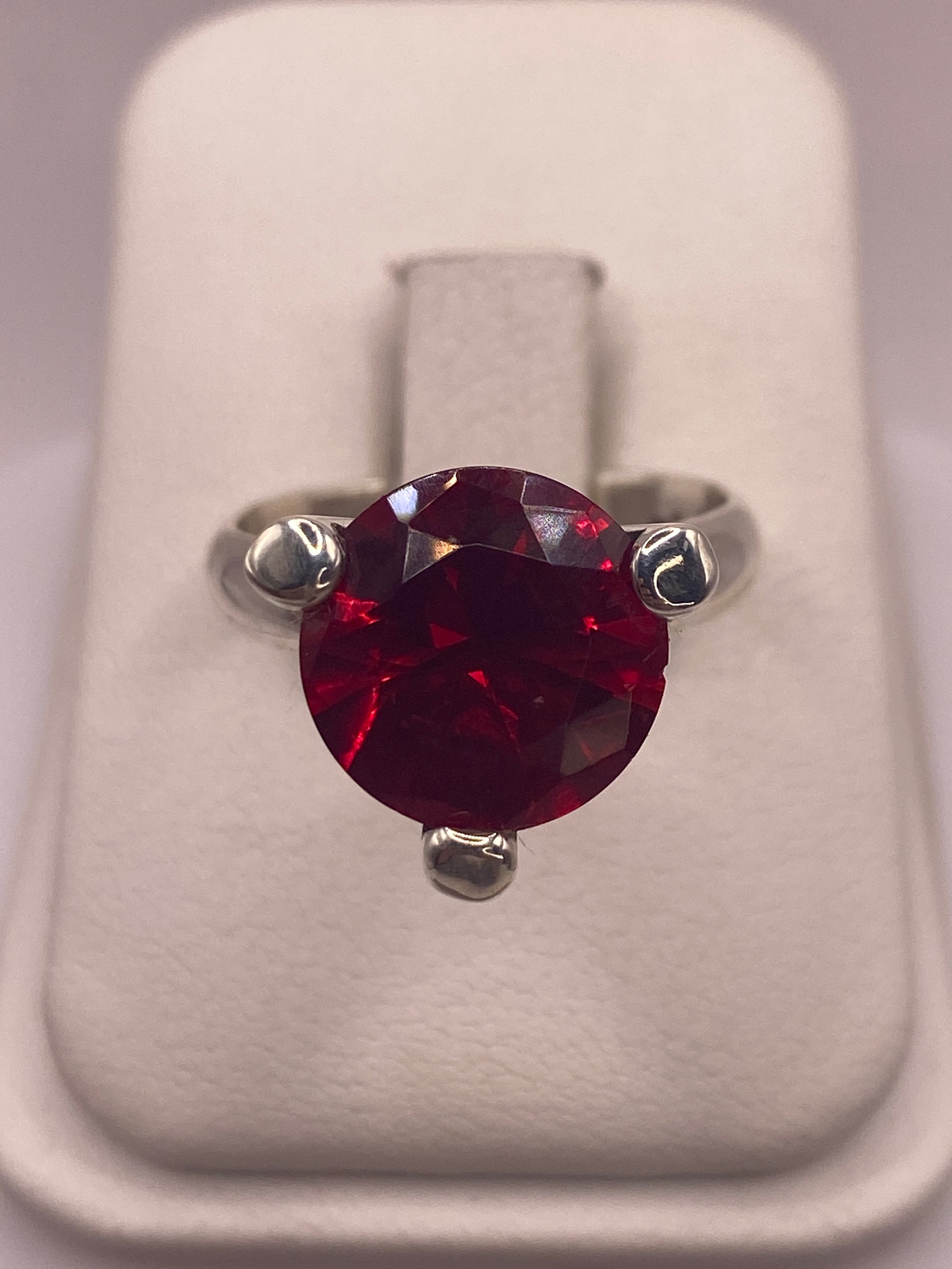 Anillo solitario de plata .925 con circonia roja facetada en la mano de una mujer