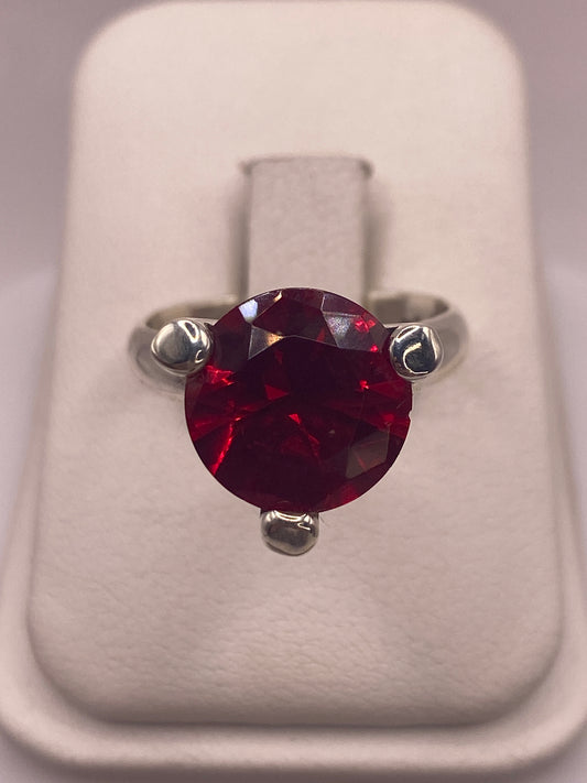Anillo solitario de plata .925 con circonia roja facetada en la mano de una mujer