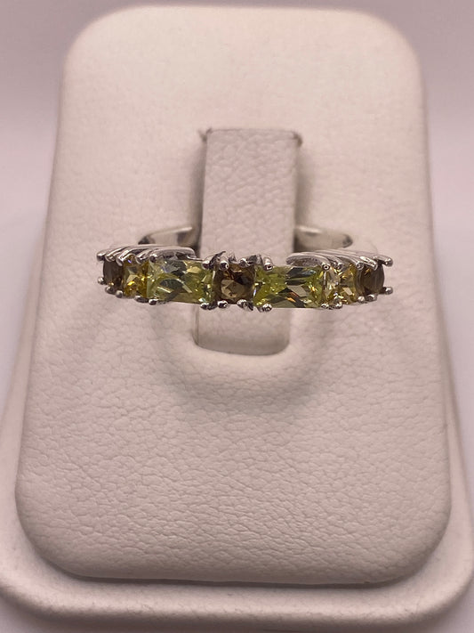 Anillo de plata con cinco circonias multicolor en línea recta, sobre soporte de terciopelo blanco