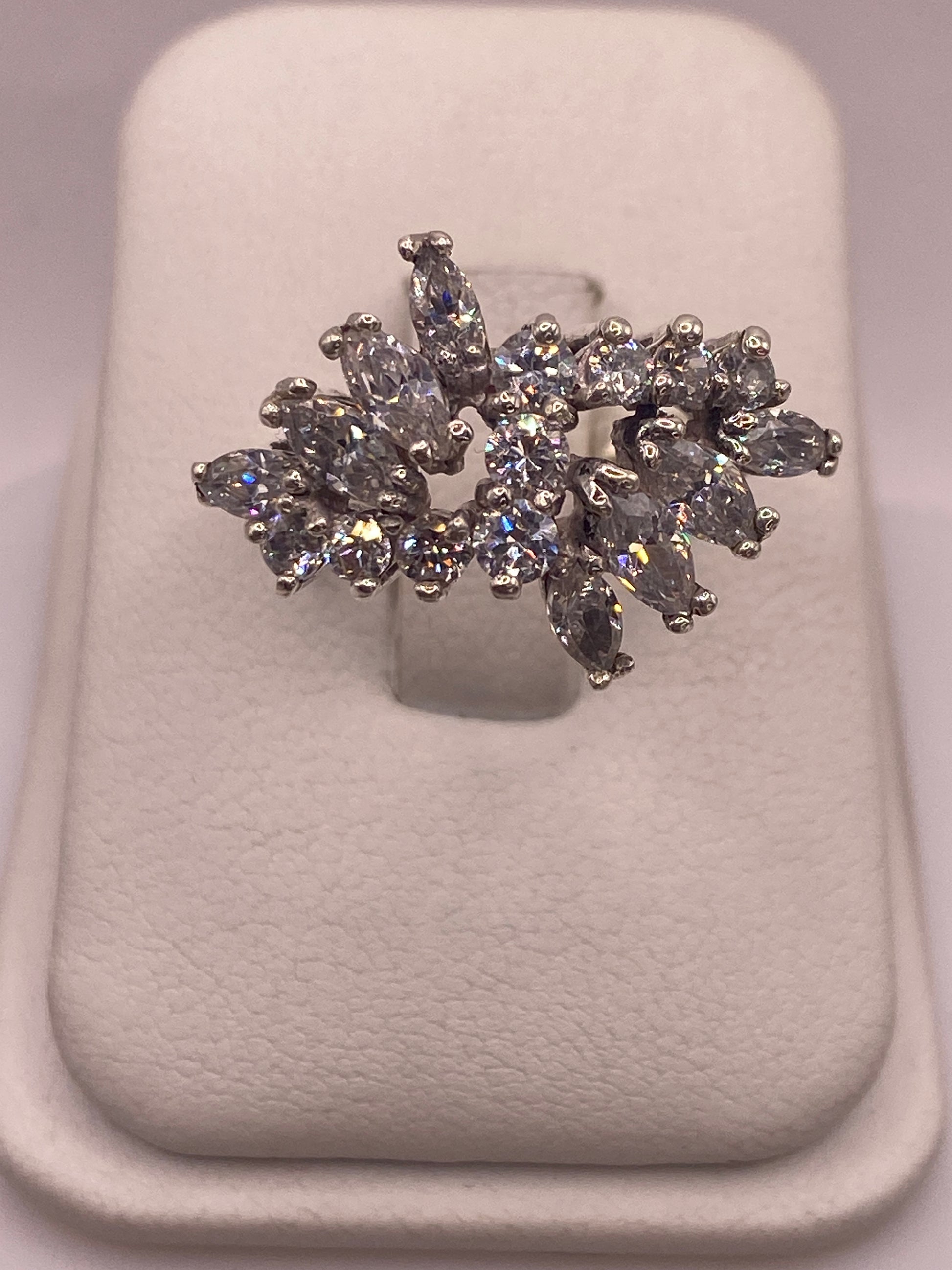 Anillo solitario de plata .925 con circonia blanca sobre cojín blanco, vista frontal mostrando el brillo del engaste
