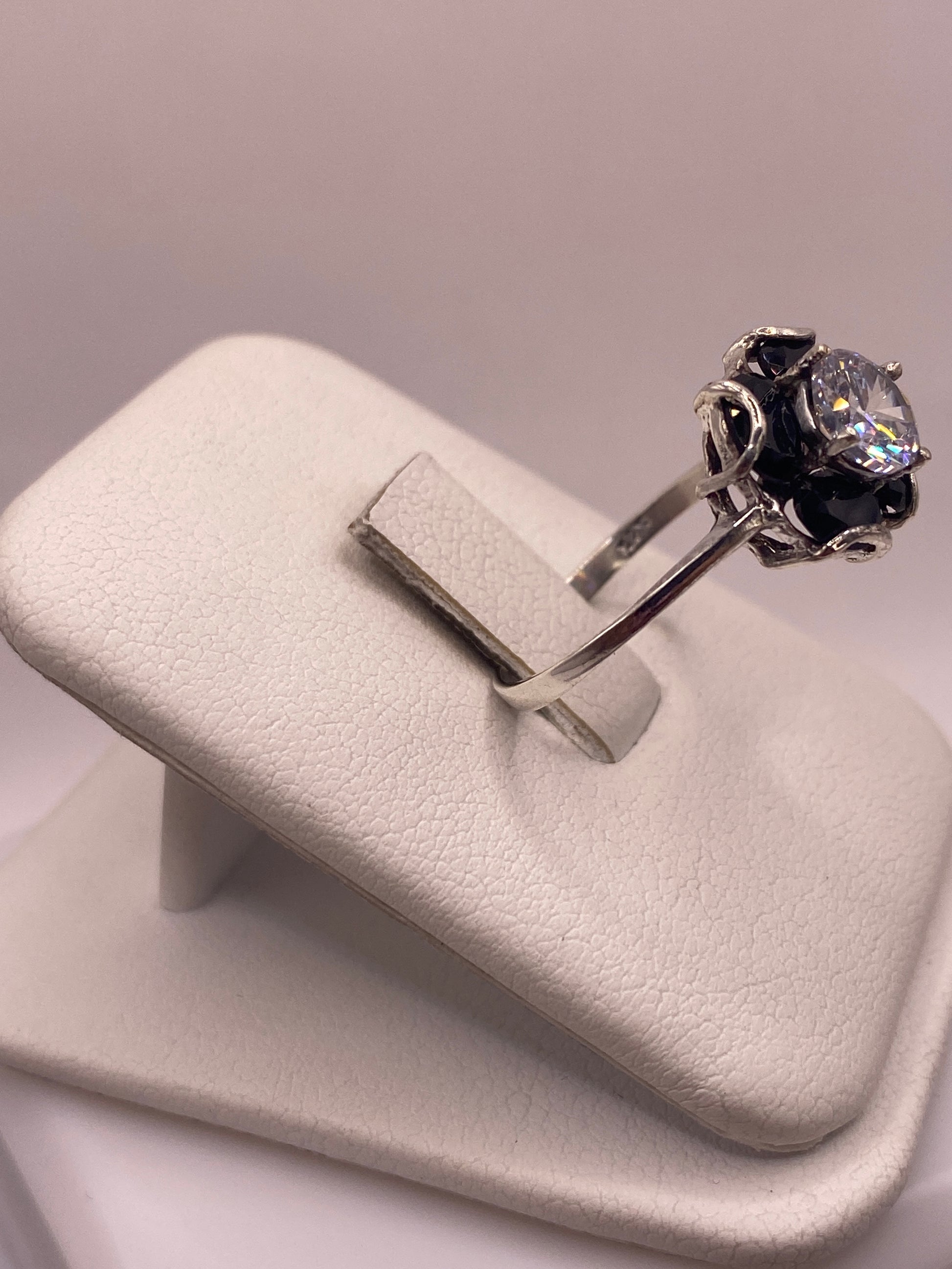 Anillo solitario plata con piedra multicolor visto de lado, mostrando el engaste a mano