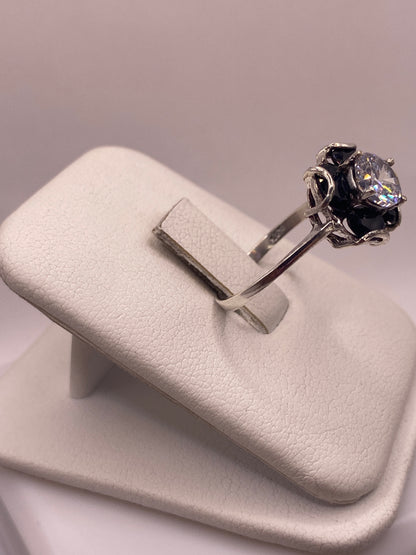 Anillo solitario plata con piedra multicolor visto de lado, mostrando el engaste a mano