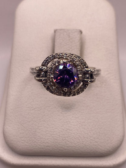 Anillo de plata solitario con circonia morada en la mano de una mujer sobre fondo blanco