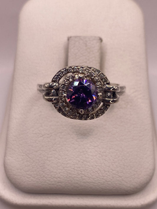 Anillo de plata solitario con circonia morada en la mano de una mujer sobre fondo blanco