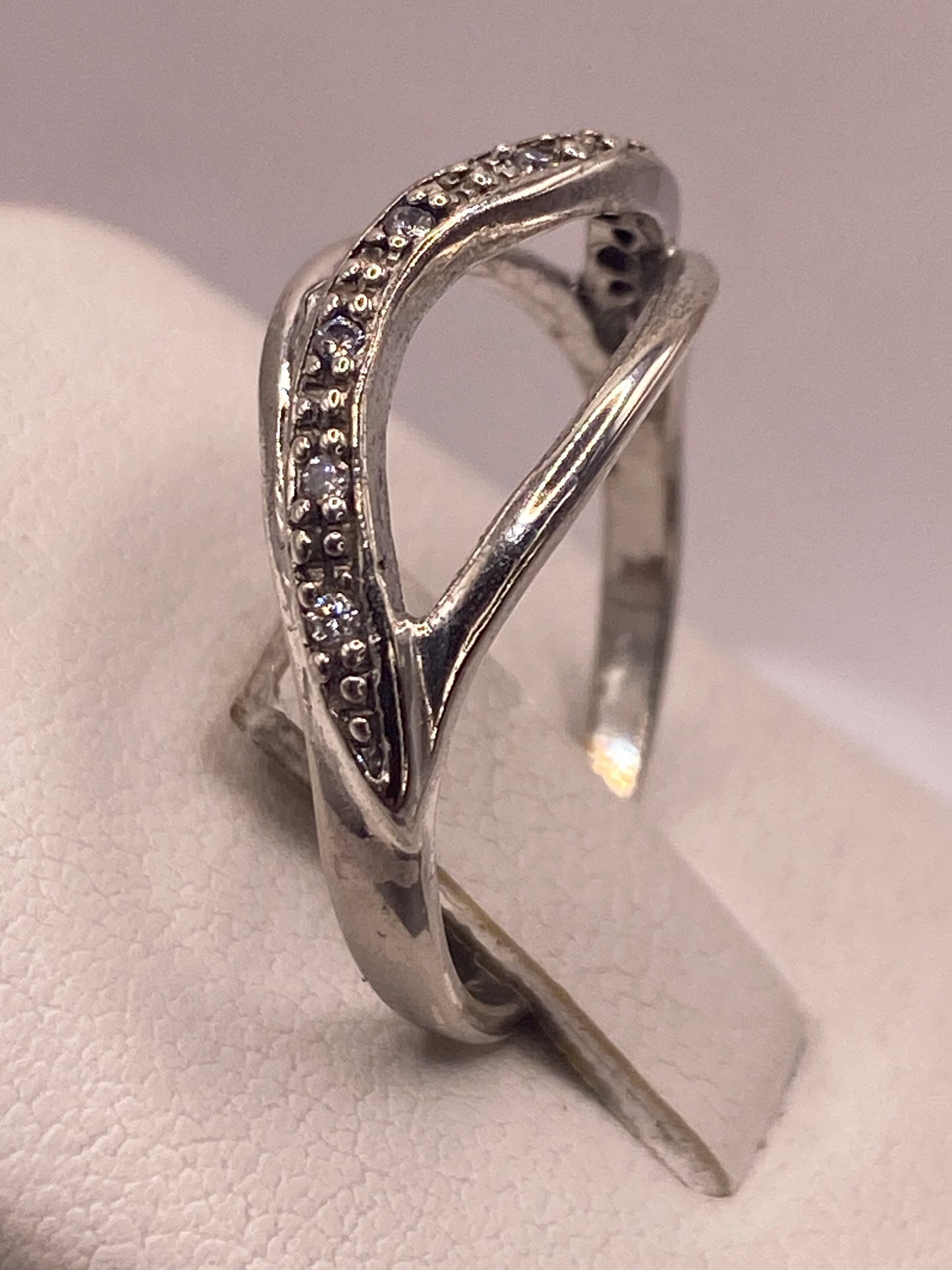 Anillo de plata cruzado puesto en mano de mujer con esmalte rosa