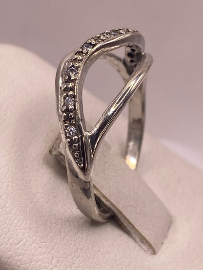 Anillo de plata cruzado puesto en mano de mujer con esmalte rosa