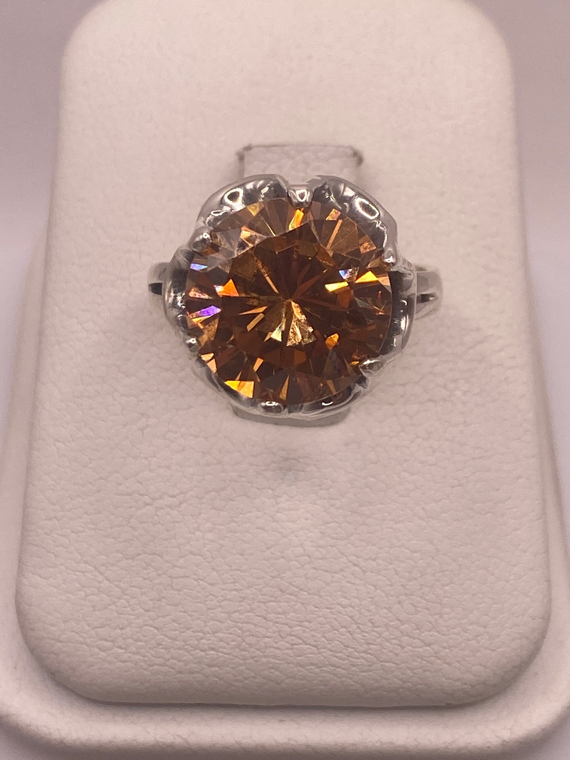 Anillo de plata .925 con circonia champagne facetada en engaste de corona, vista frontal sobre estuche blanco