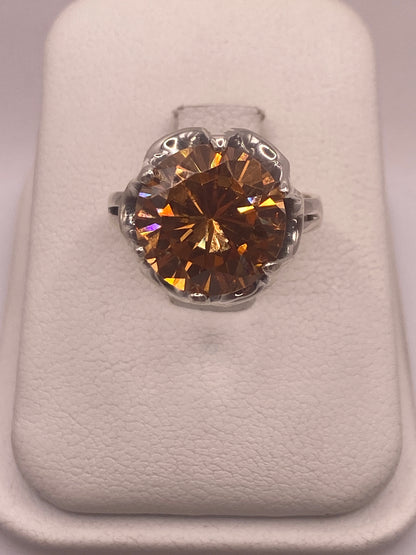 Anillo de plata .925 con circonia champagne facetada en engaste de corona, vista frontal sobre estuche blanco