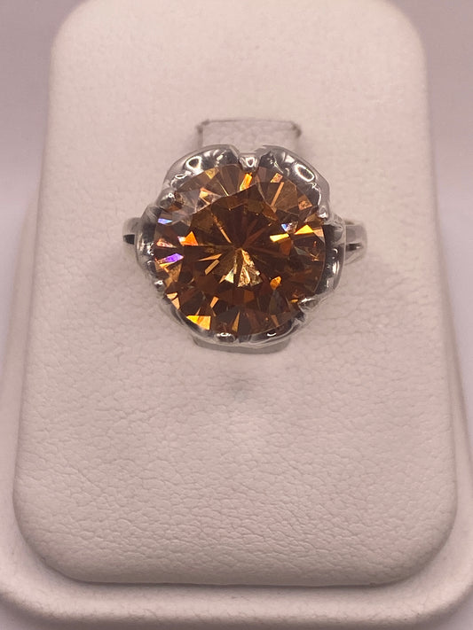 Anillo de plata .925 con circonia champagne facetada en engaste de corona, vista frontal sobre estuche blanco