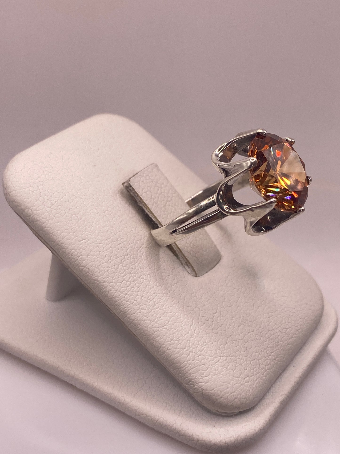 Solitario de circonia champagne en plata .925 mostrado en la mano, detalles del brillo multicolor y la banda pulida