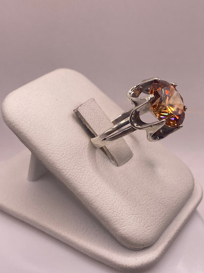 Solitario de circonia champagne en plata .925 mostrado en la mano, detalles del brillo multicolor y la banda pulida