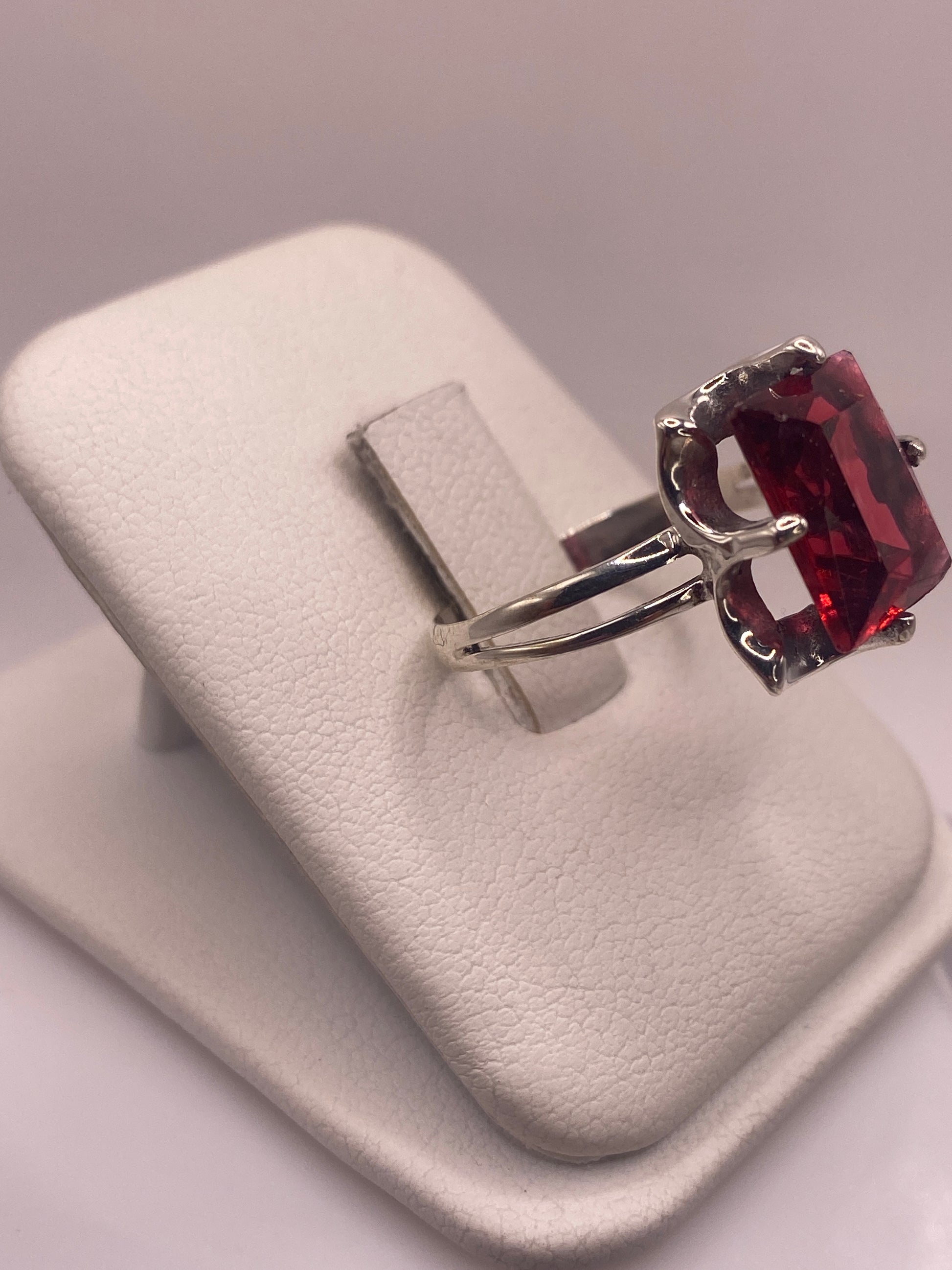 Anillo solitario circonia roja en la mano, mostrando el fuego rojo intenso