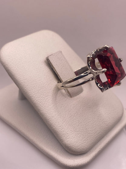 Anillo solitario circonia roja en la mano, mostrando el fuego rojo intenso