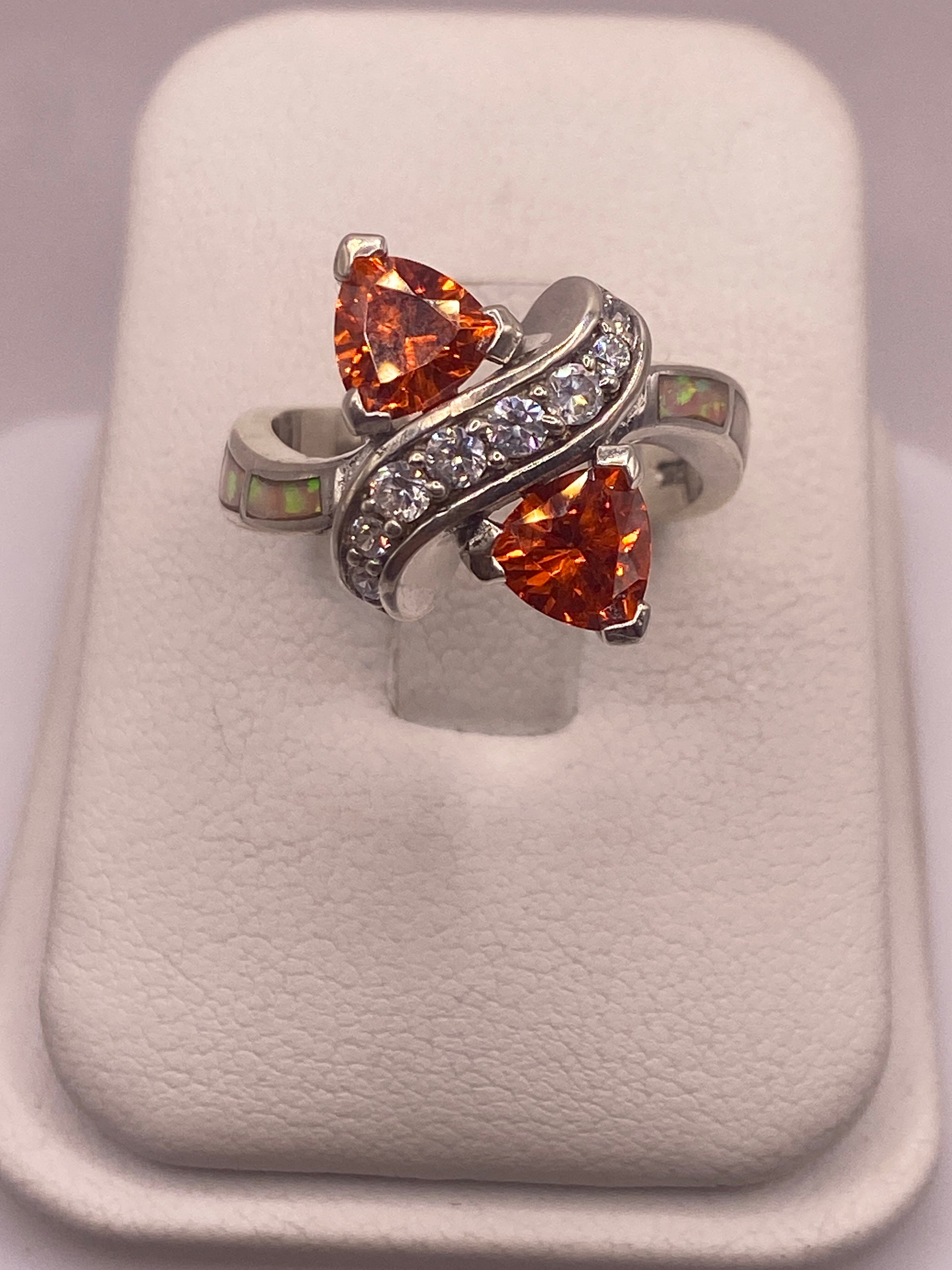 Anillo de plata solitario con circonia naranja triangular brillante en la mano de una mujer