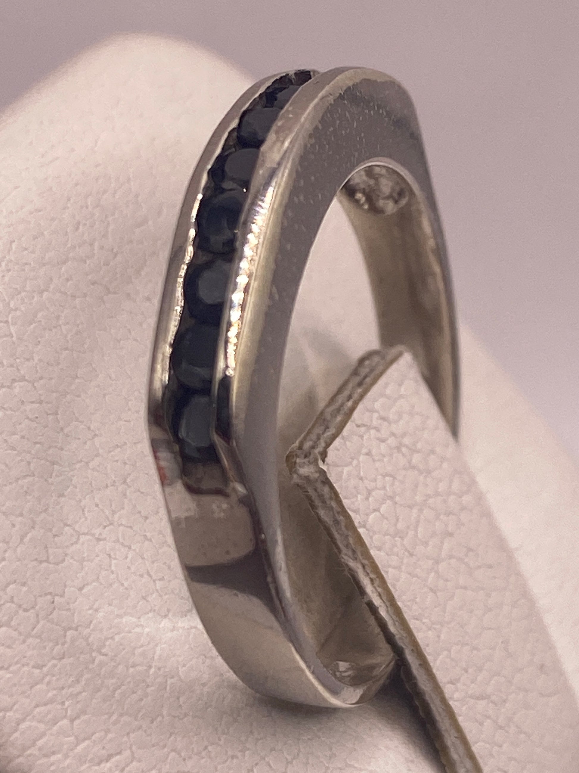 Anillo de plata con circonia negra en la mano de una mujer con esmalte rosado