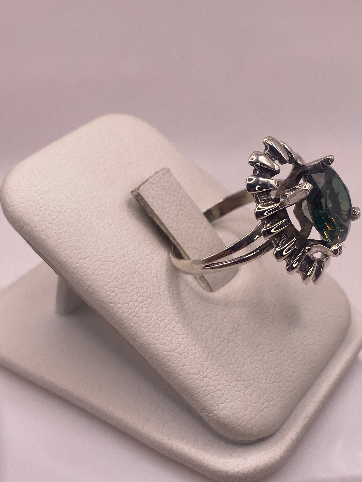 Anillo solitario verde en la mano, mostrando el halo escalonado en plata