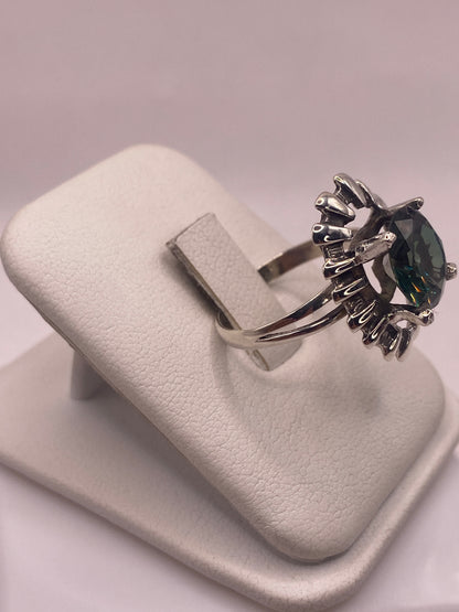 Anillo solitario verde en la mano, mostrando el halo escalonado en plata