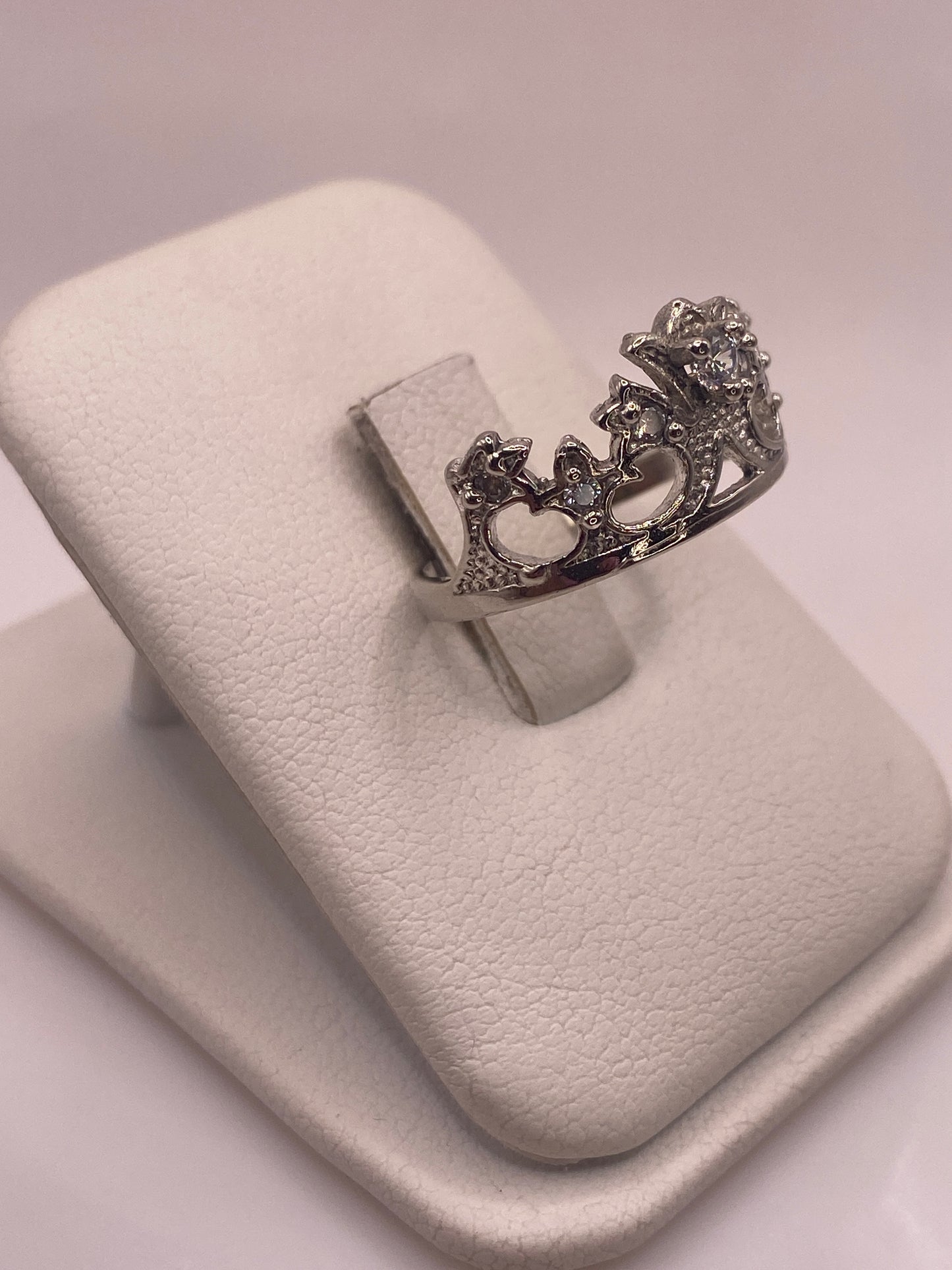 Anillo de plata con piedra blanca engastada, vista lateral mostrando los detalles decorativos